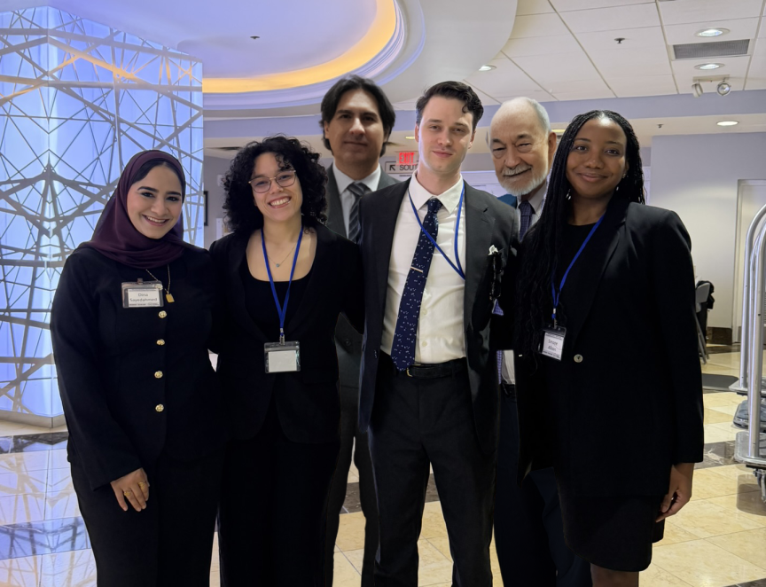 Six people standing in a row and smiling, wearing business clothing