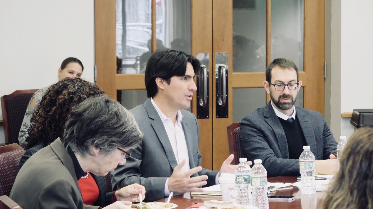 Jorge Contesse sitting at a table while speaking and other people sitting around him listen